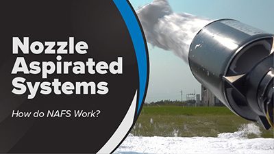 A black foam nozzle sprays white foam over a field. White text reads Nozzle Aspirated Systems; HOw do NAFS Work?